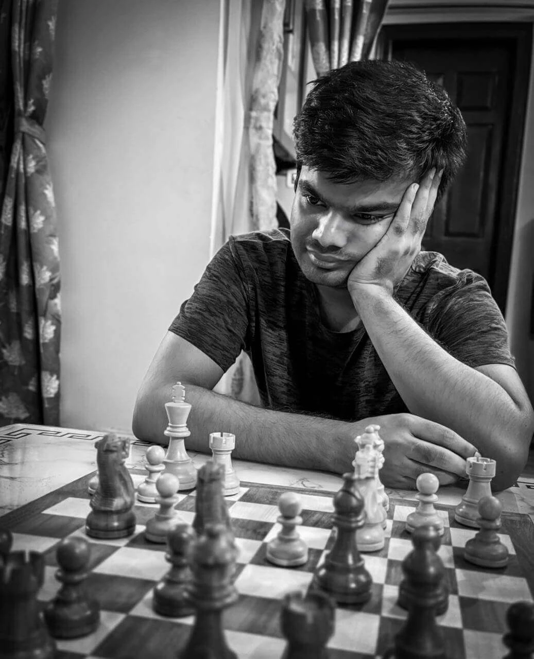 Raj focused on a chess game, contemplating his next move.